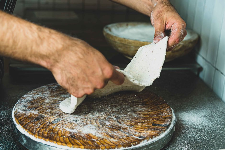 Mains façonnant une pâte à pizza fraîche recouverte de farine